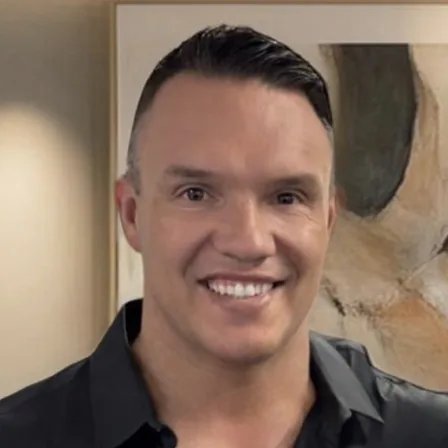 Alex McPhee, photographed in front of a framed painting.